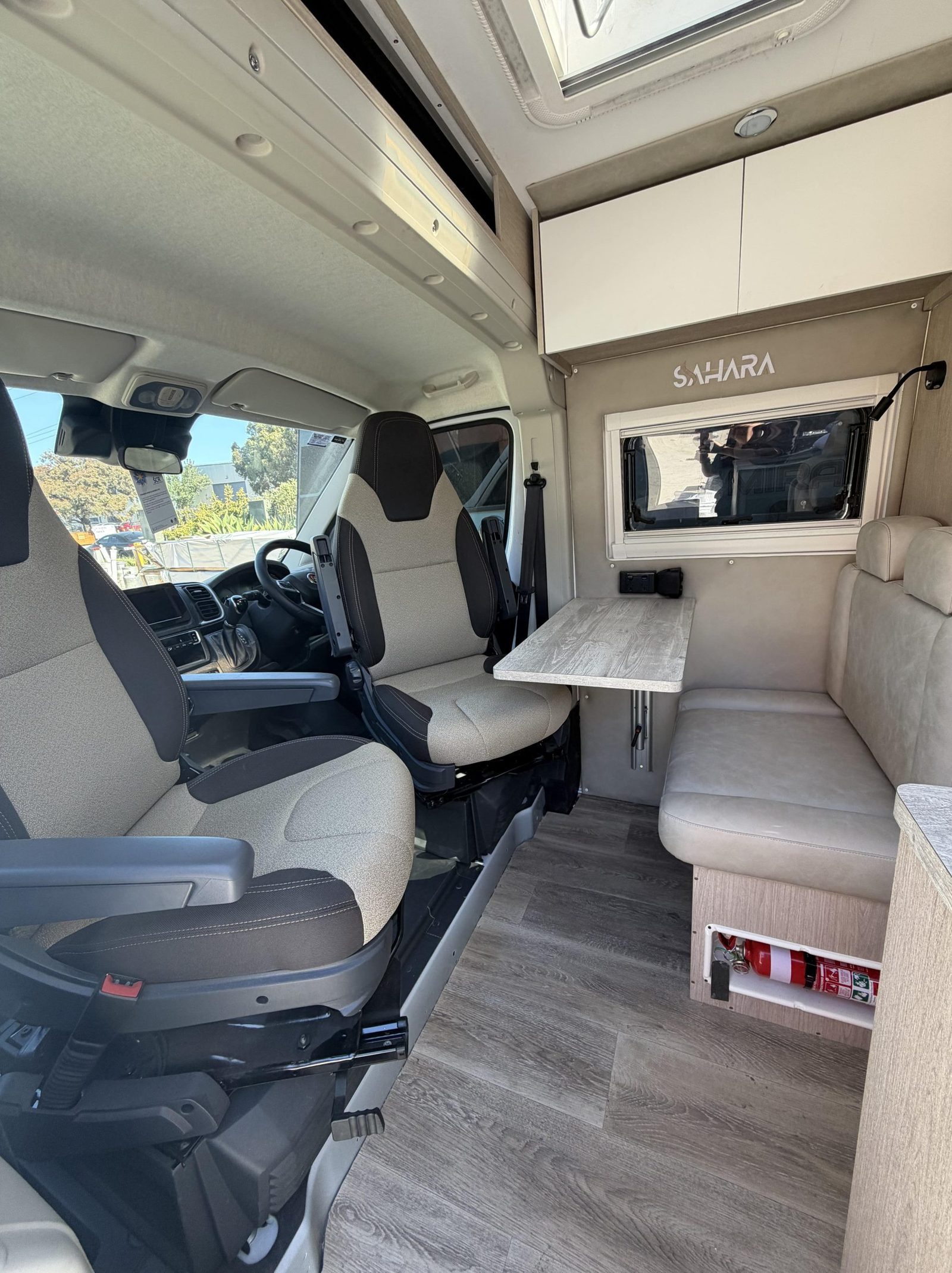 Swivel cab seats facing a dining table inside a Sahara van build